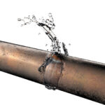 Close-up of a leaking corroded pipe spraying water, illustrating why pipes burst in Toronto during spring.