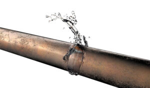 Close-up of a leaking corroded pipe spraying water, illustrating why pipes burst in Toronto during spring.