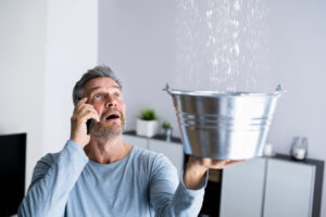 Owner on phone, trying to stop leak with bucket